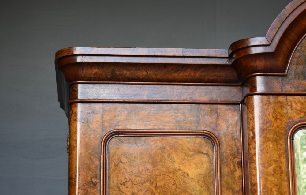 A Victorian burr walnut triple wardrobe featuring an arched central mirrored door flanked by two panelled timber doors with carved mouldings. View IV