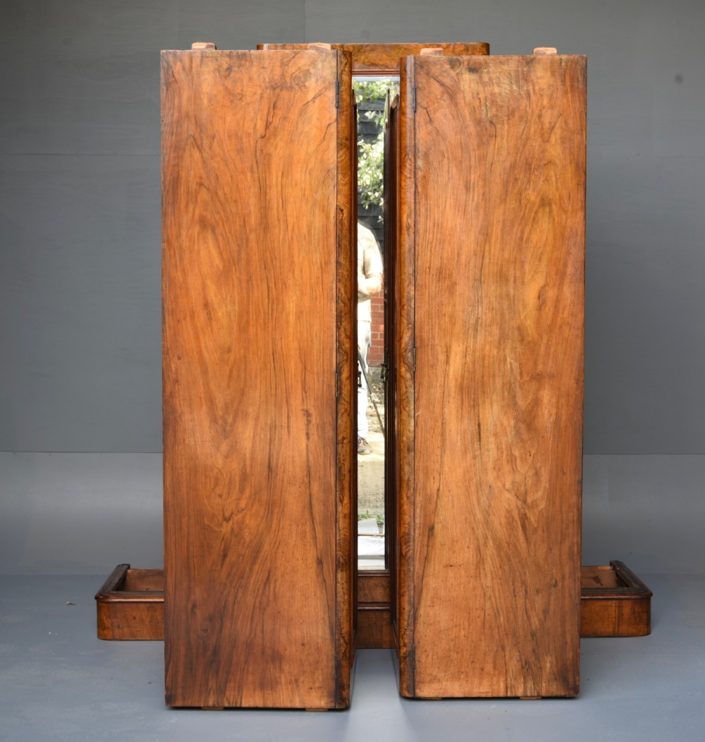 A Victorian burr walnut triple wardrobe featuring an arched central mirrored door flanked by two panelled timber doors with carved mouldings. View VII