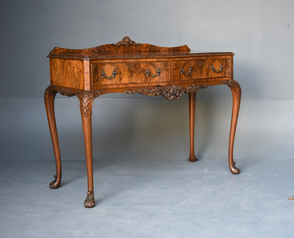 A Queen Anne style burr walnut side table featuring two drawers with brass handles, carved cabriole legs, and a raised gallery top.