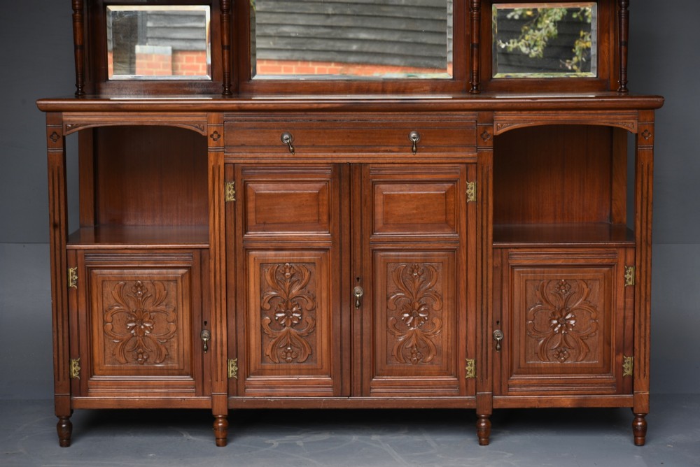 A carved Victorian walnut sideboard with a three-panel mirrored superstructure, spindle galleries, and lower cupboard doors decorated with floral carved panels. View II