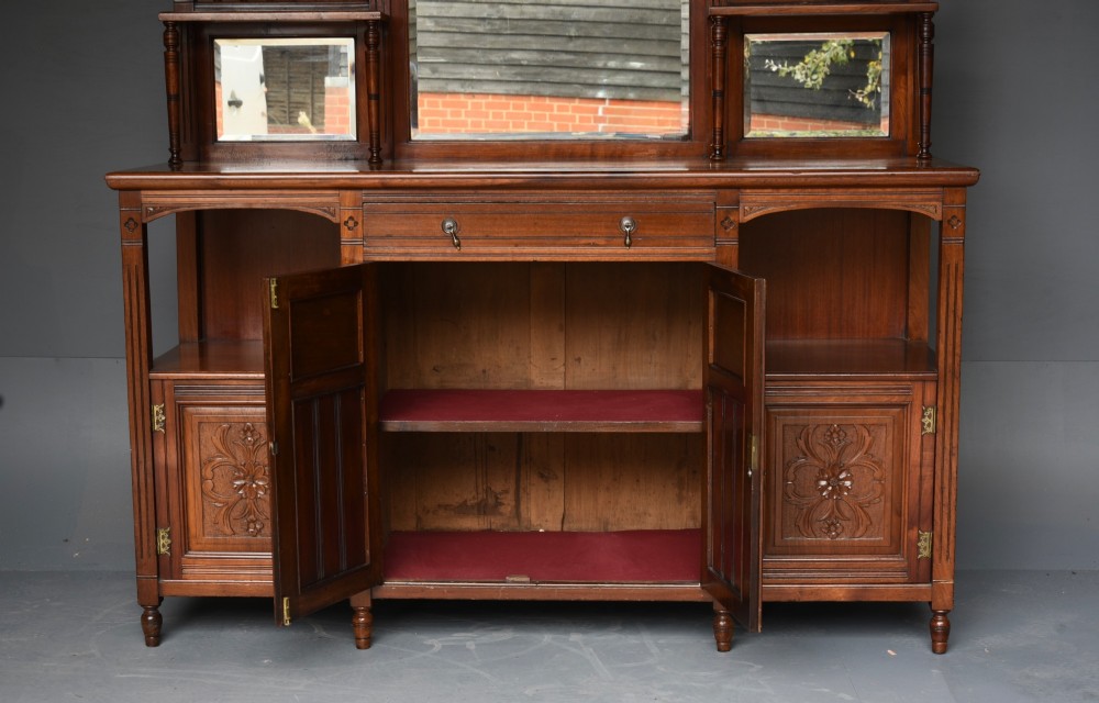 A carved Victorian walnut sideboard with a three-panel mirrored superstructure, spindle galleries, and lower cupboard doors decorated with floral carved panels. View VI