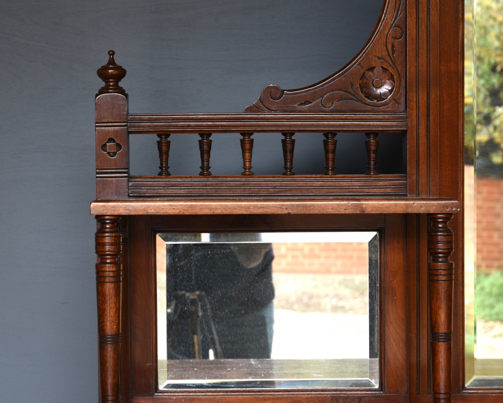 A carved Victorian walnut sideboard with a three-panel mirrored superstructure, spindle galleries, and lower cupboard doors decorated with floral carved panels. View VIII