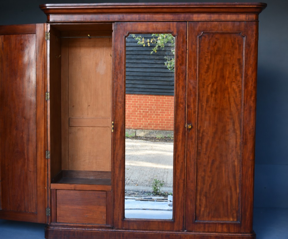 A Victorian mahogany triple wardrobe featuring two outer panelled doors, a central mirrored door, and a moulded cornice top. View III