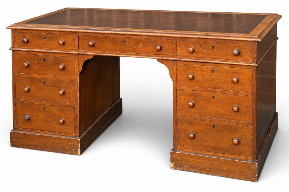 A Victorian oak pedestal desk featuring a red leather inset top, wooden knob handles, and multiple drawers on twin pedestals. View III