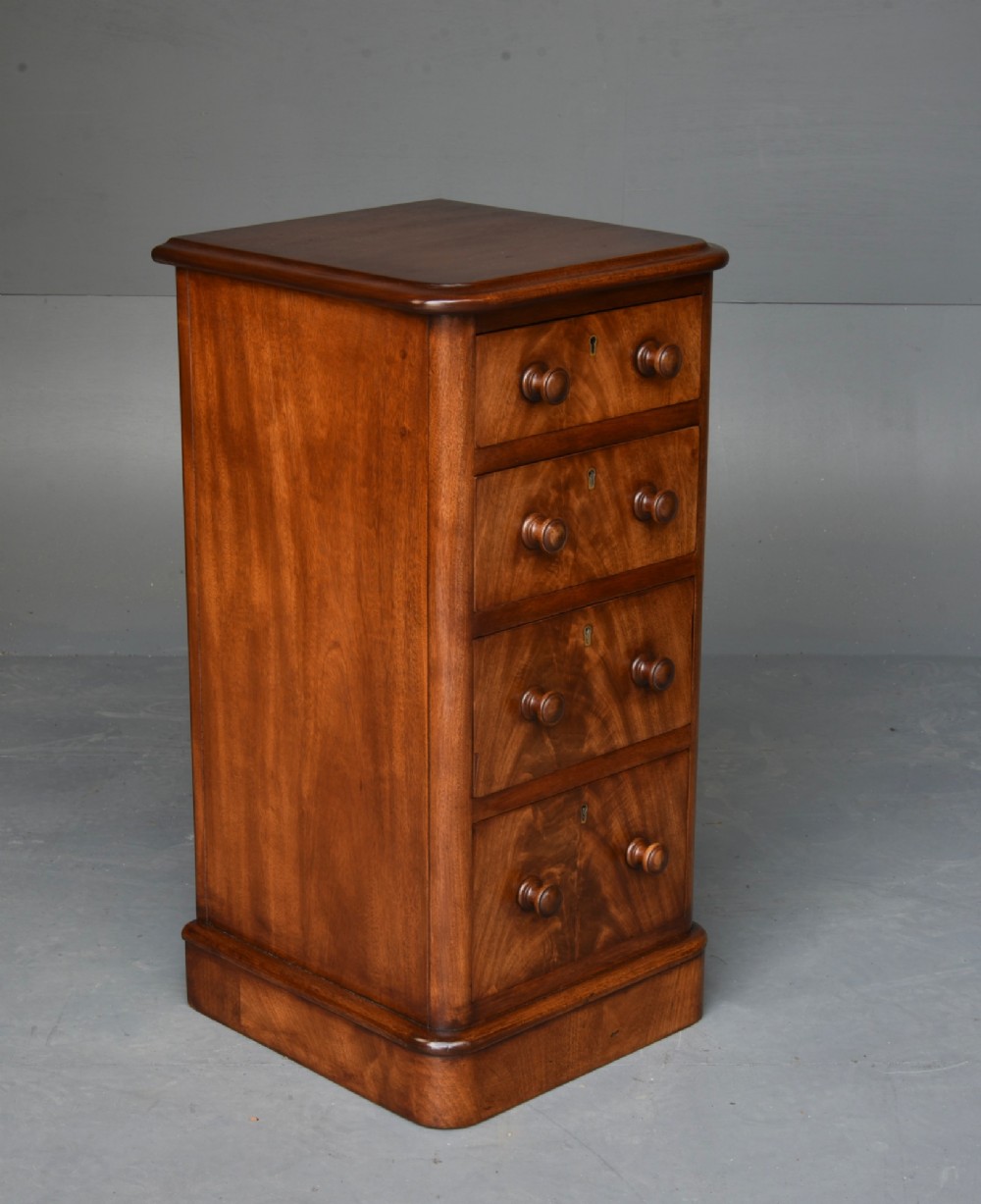 A matching pair of tall Victorian mahogany bedside chests featuring four graduated drawers with turned wooden handles and a plinth base. View V