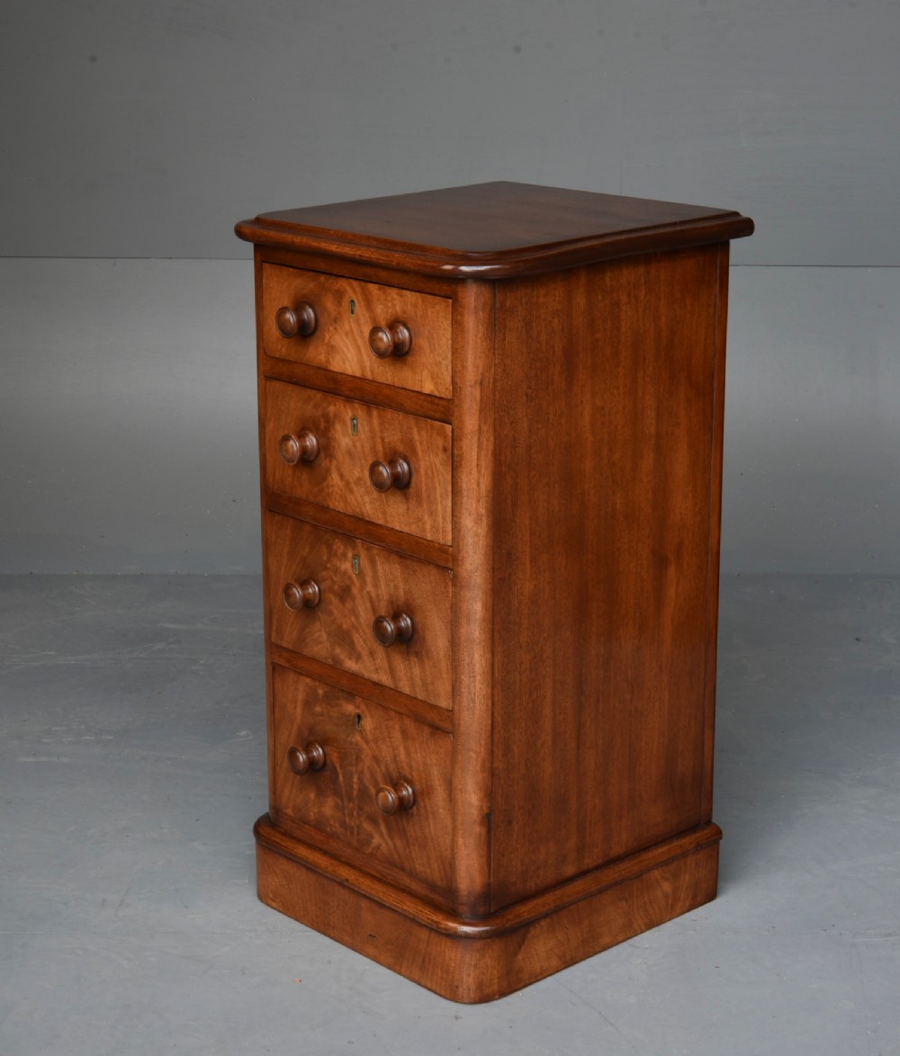 A matching pair of tall Victorian mahogany bedside chests featuring four graduated drawers with turned wooden handles and a plinth base. View VI