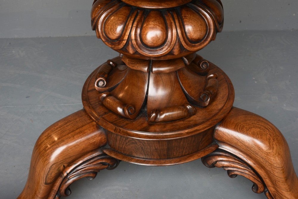 A nineteenth-century circular mahogany tilt-top table with radial flame mahogany veneering set on a carved tripod base with scroll feet. View VII