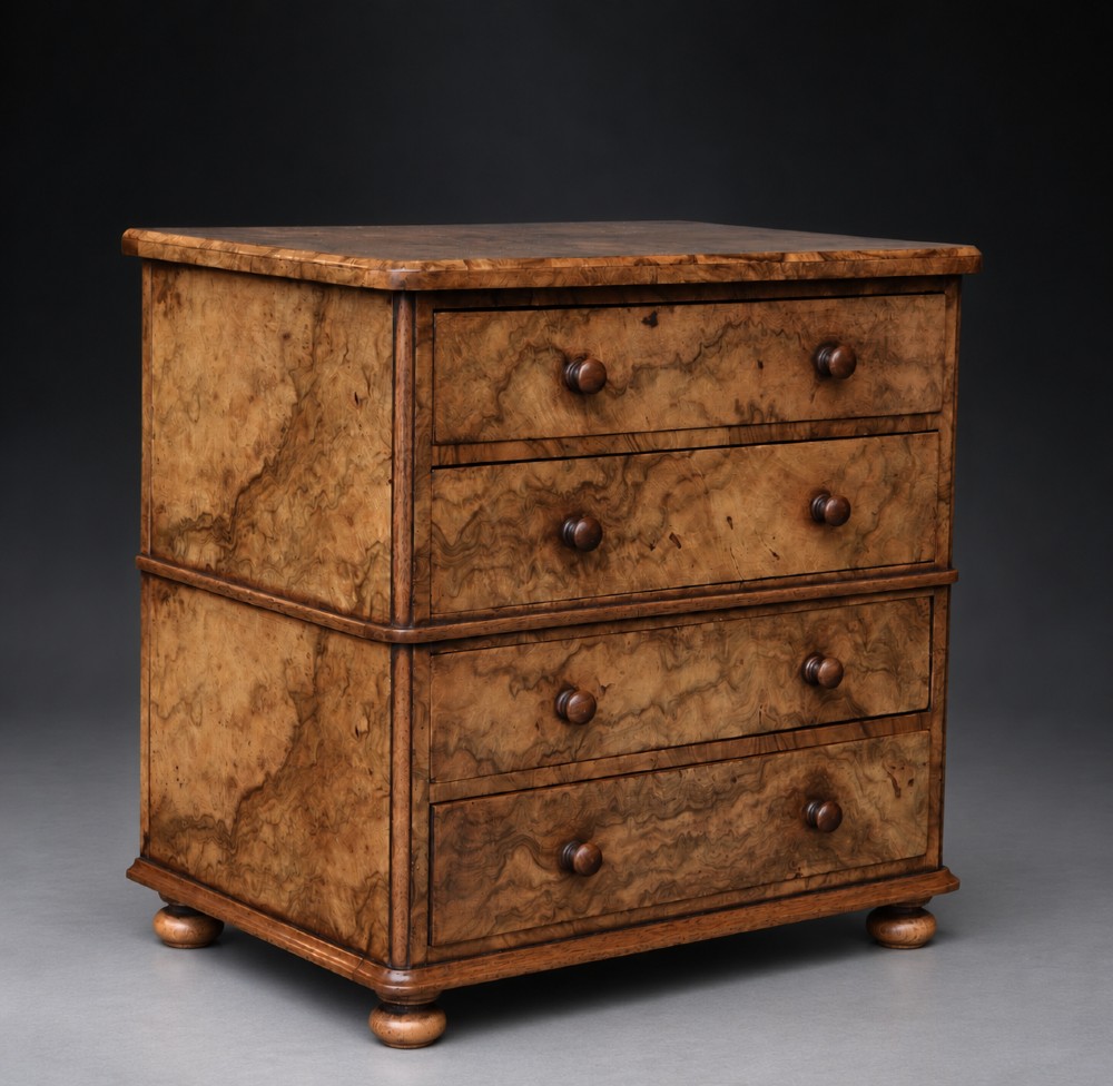 A small antique burr walnut chest of four drawers featuring distinctive swirl grain patterns, turned wooden knobs, and low turned feet. View II