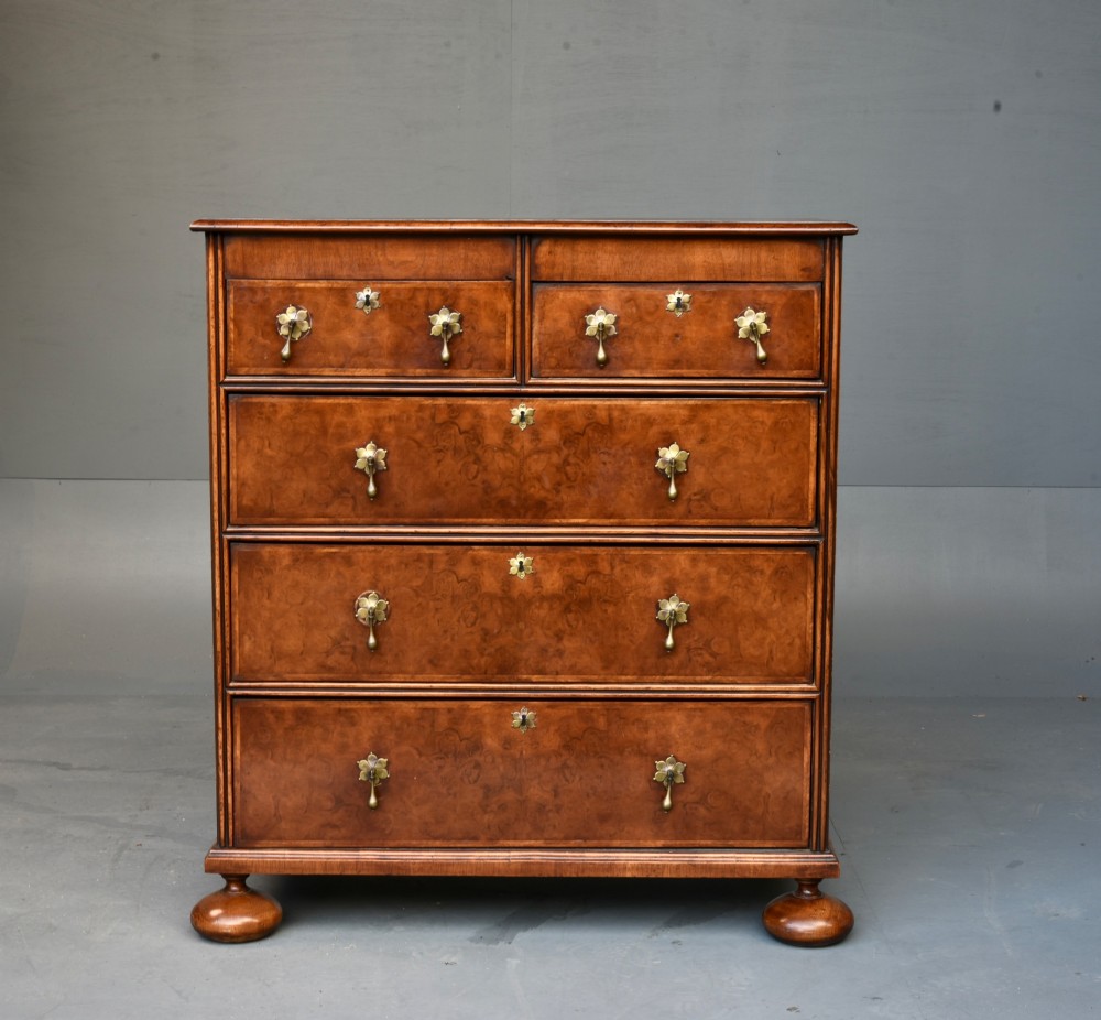 A 19th-century Queen Anne style walnut chest of drawers featuring a two-over-three drawer configuration with brass drop handles and bun feet.