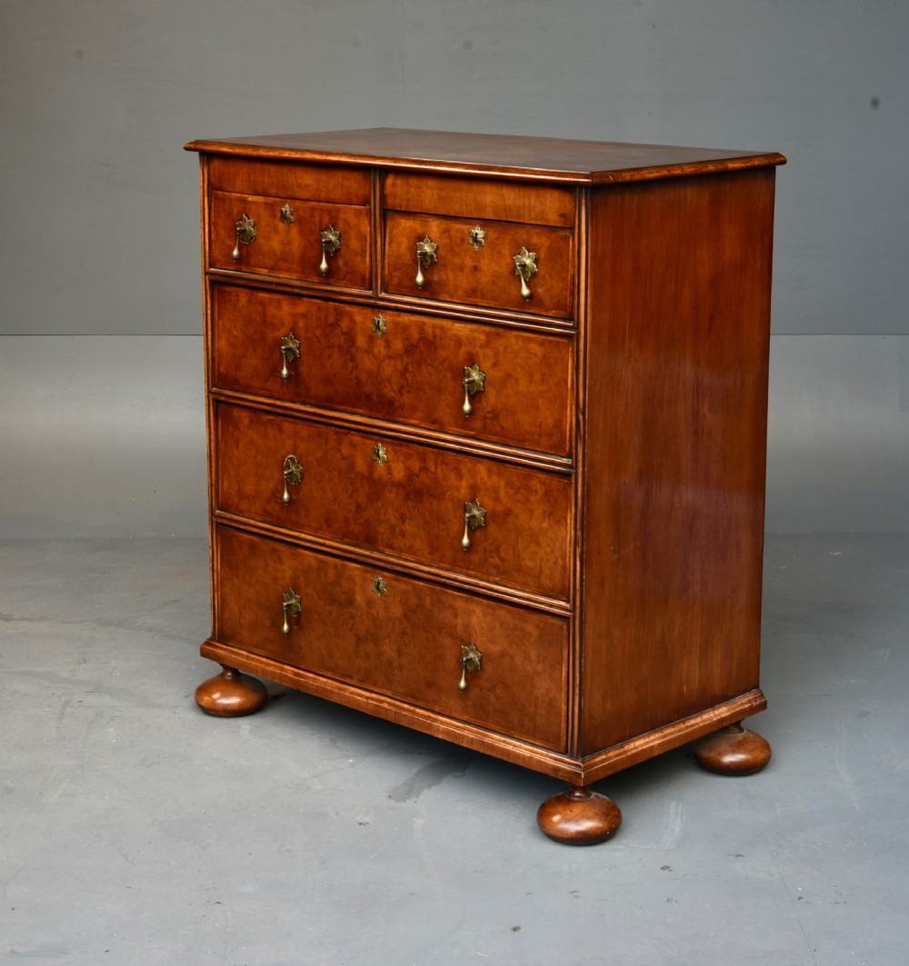 A 19th-century Queen Anne style walnut chest of drawers featuring a two-over-three drawer configuration with brass drop handles and bun feet. View III