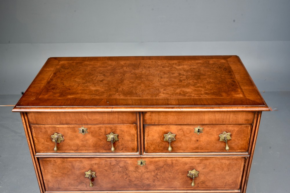 A 19th-century Queen Anne style walnut chest of drawers featuring a two-over-three drawer configuration with brass drop handles and bun feet. View VI