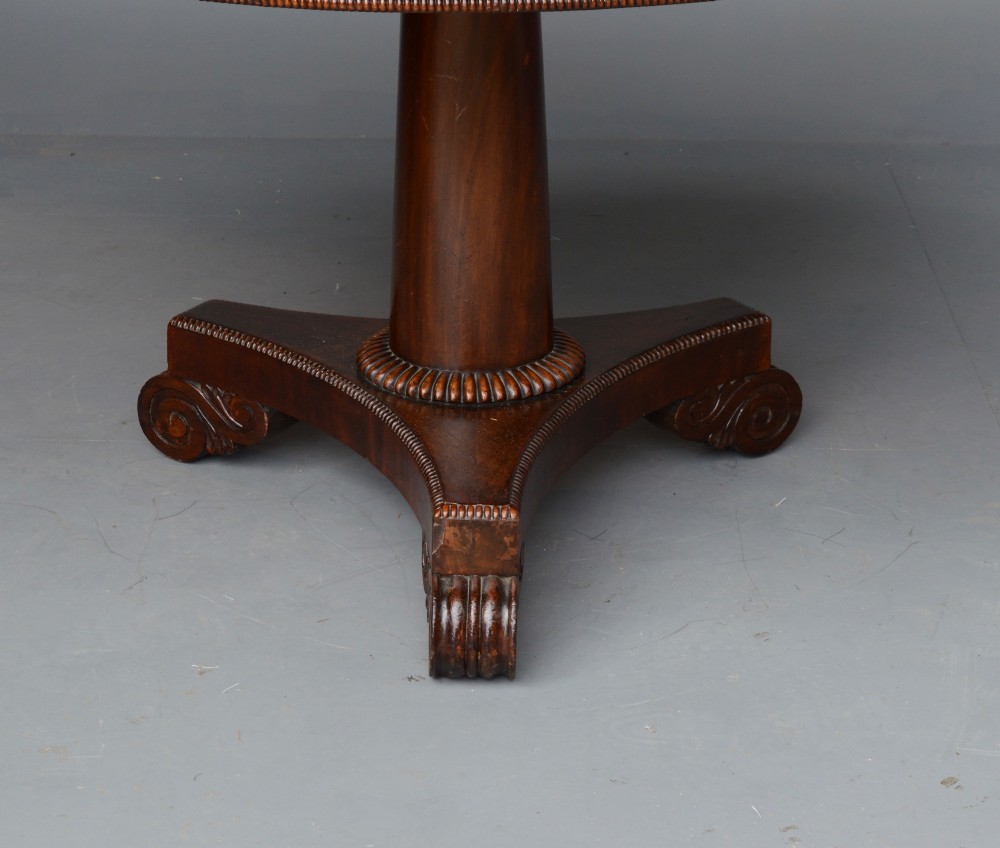 An early 19th-century Regency tilt-top table with a circular flame mahogany veneered top on a central pedestal base. View III