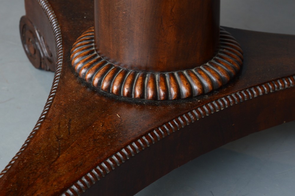 An early 19th-century Regency tilt-top table with a circular flame mahogany veneered top on a central pedestal base. View IV