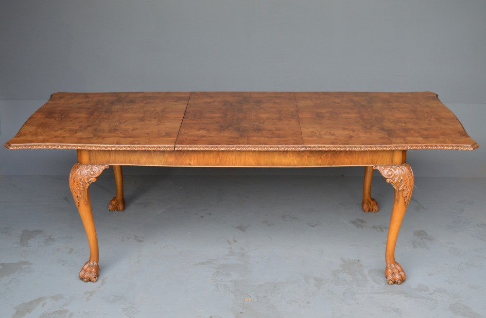 A figured walnut Queen Anne style extending dining table surrounded by eight matching splat-back chairs with carved cabriole legs and upholstered seat cushions. View II