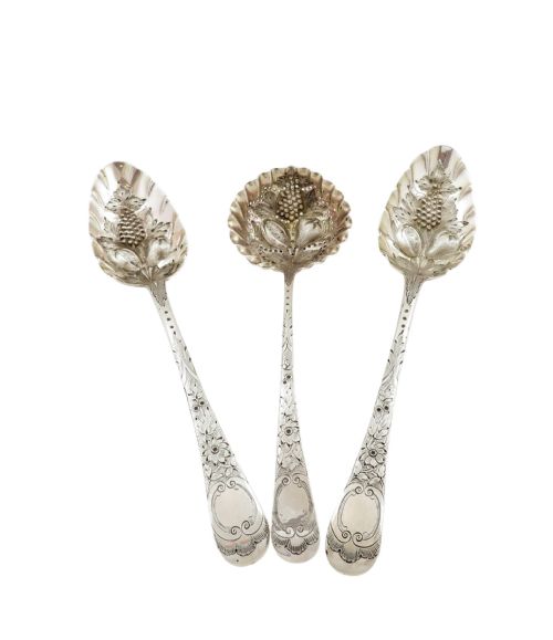 fig 1. A fitted plum fabric-lined presentation case displaying two embossed sterling silver berry spoons and one pierced silver sugar sifter spoon.