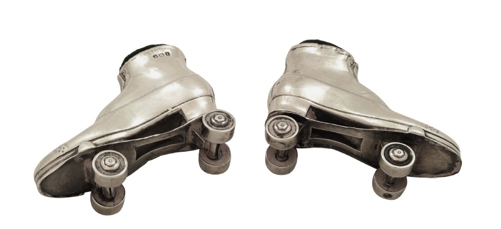 A pair of Edwardian sterling silver roller skate boots fitted with dark green velvet pin cushion tops. View V