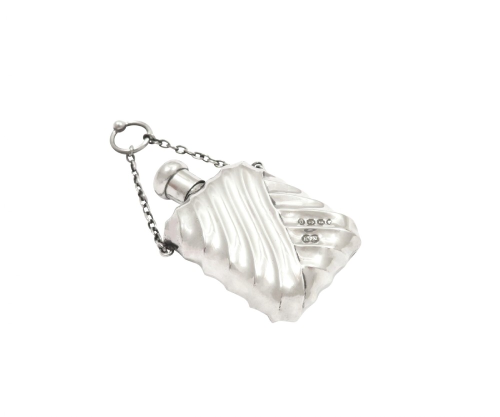 An antique Victorian sterling silver scent flask featuring repousse fluting and an attached hanging chain. View V