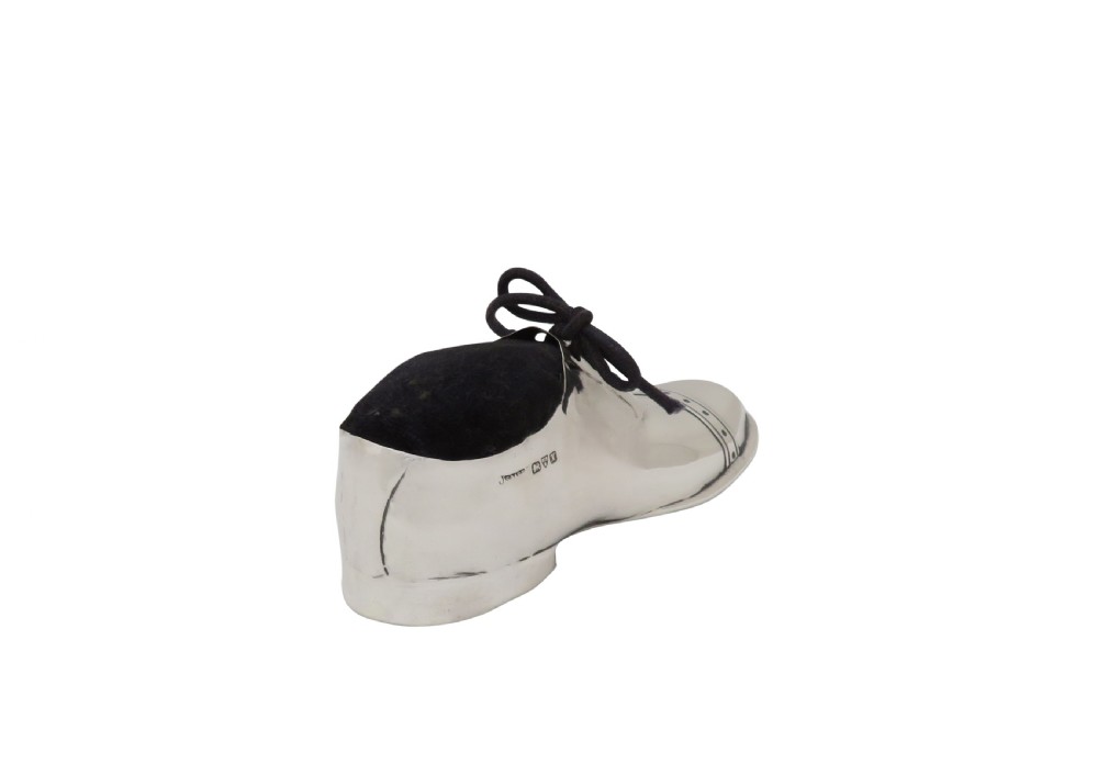An Edwardian sterling silver pin cushion crafted in the shape of a shoe with a black velvet pad and fabric laces. View V