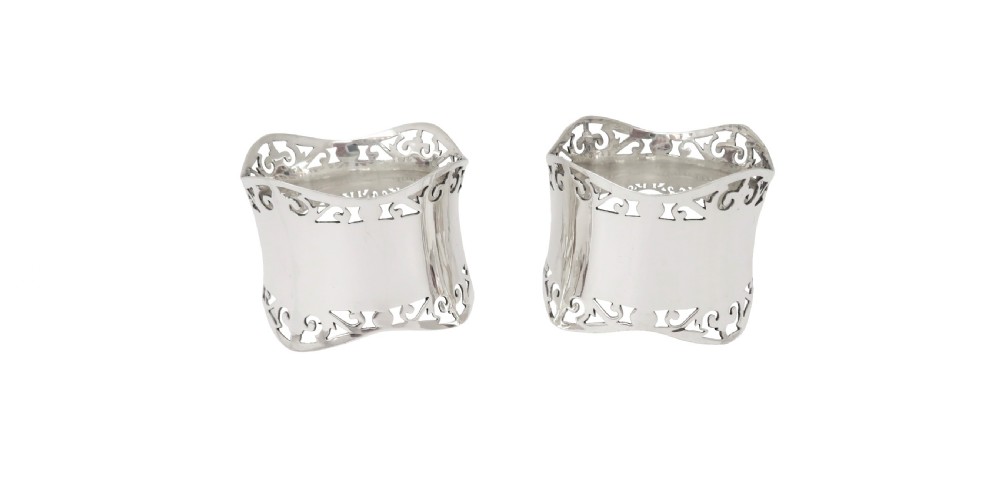 A pair of hallmarked sterling silver napkin rings with pierced borders, presented inside an open black fitted case lined with green satin. View VII