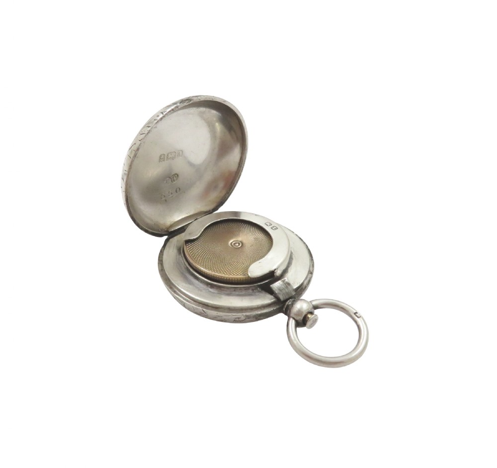 A circular Victorian sterling silver sovereign case with hand-engraved scroll patterns, a blank shield cartouche, and a top suspension ring. View VI