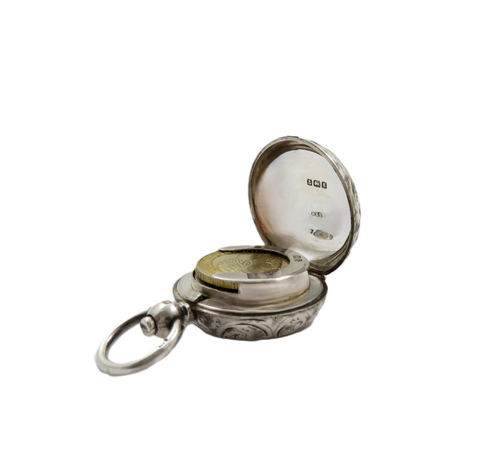 A circular Edwardian sterling silver sovereign case decorated with hand-engraved foliate scrollwork and featuring a top suspension ring. View II