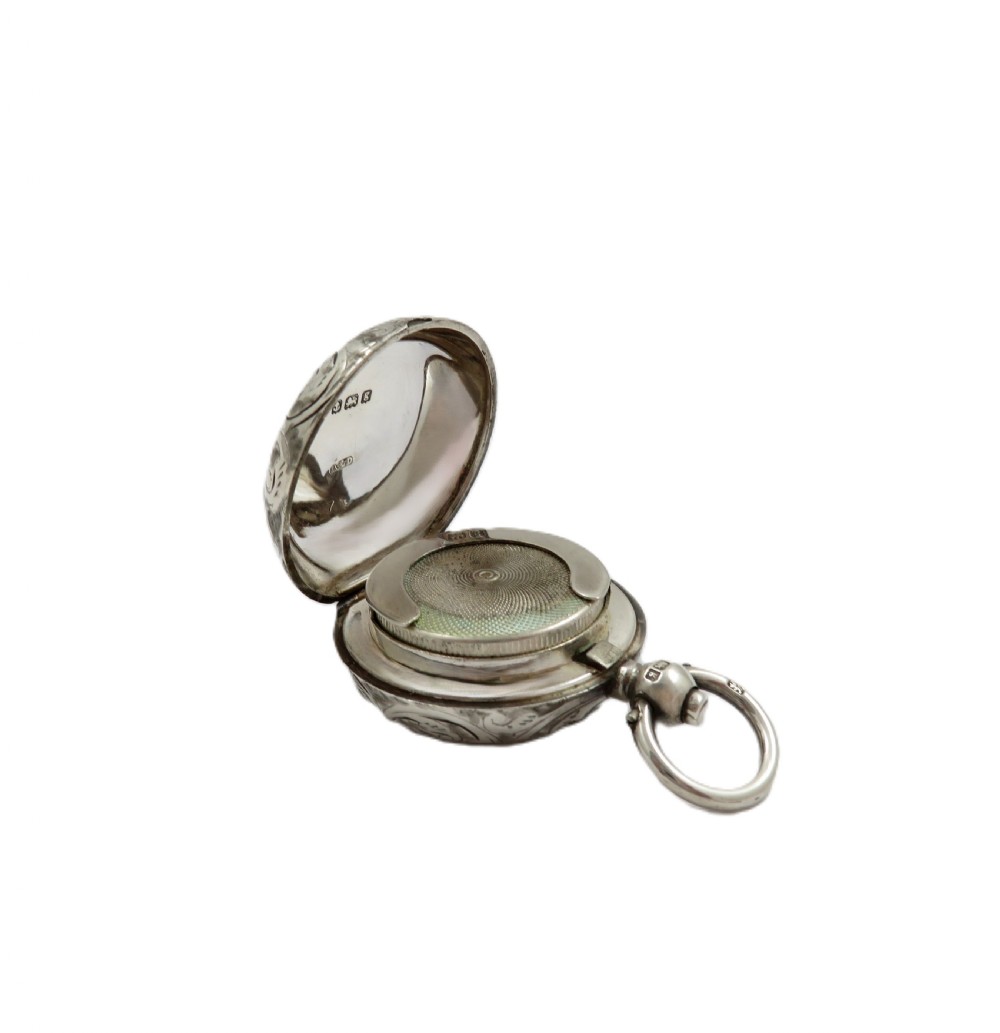 A circular Edwardian sterling silver sovereign case decorated with hand-engraved foliate scrollwork and featuring a top suspension ring. View VIII