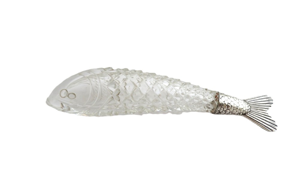 A Victorian clear cut glass scent bottle carved in the shape of a fish with a textured sterling silver tail cap. View VIII