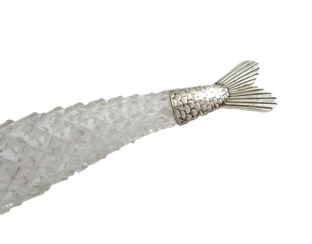 A Victorian clear cut glass scent bottle carved in the shape of a fish with a textured sterling silver tail cap. View IX