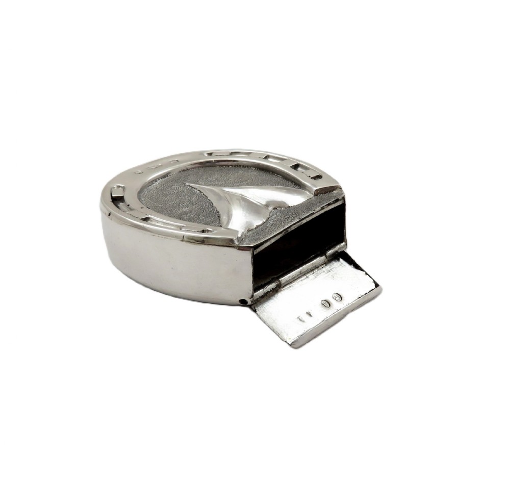 A Victorian sterling silver vesta case in the shape of a horseshoe featuring textured detailing and engraved lettering. View V