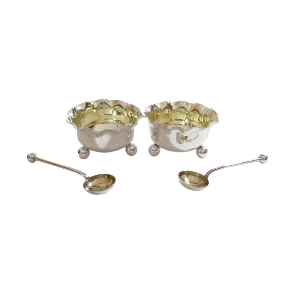 A pair of Victorian sterling silver open salt cellars with crimped rims and matching spoons set inside a blue velvet presentation case. View III