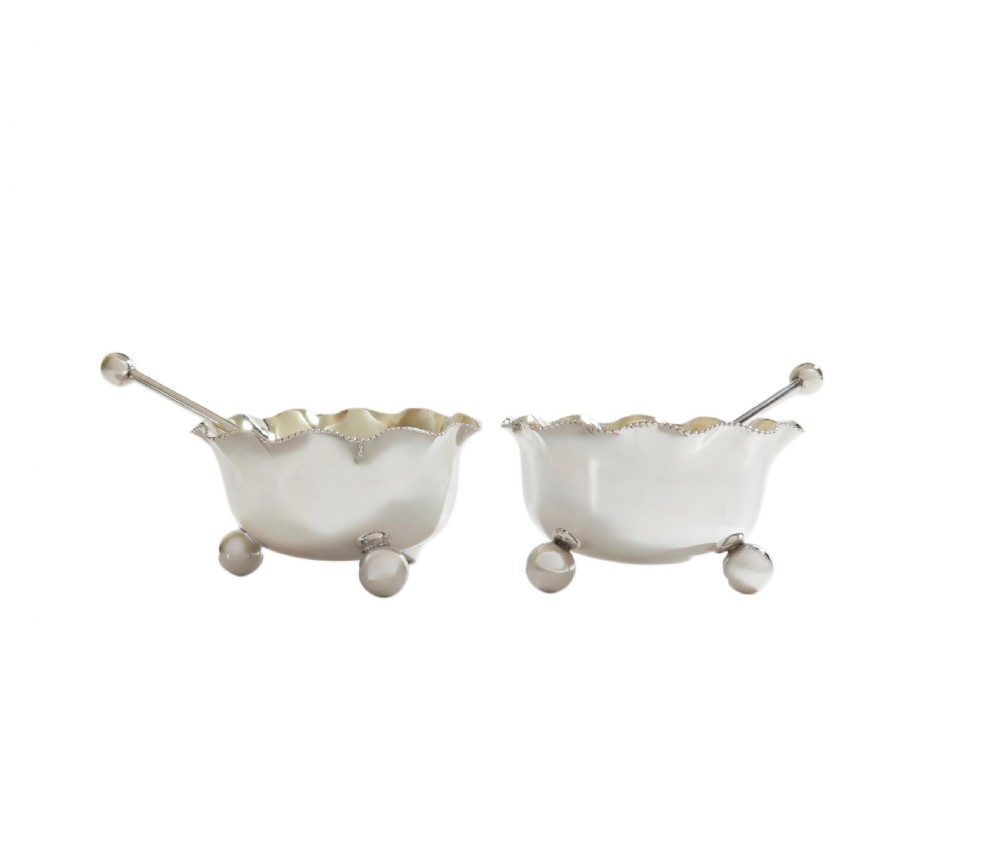 A pair of Victorian sterling silver open salt cellars with crimped rims and matching spoons set inside a blue velvet presentation case. View V