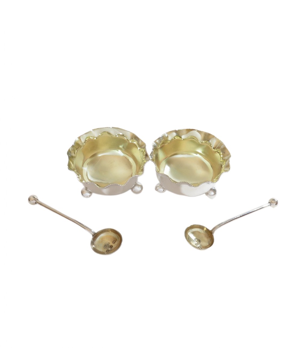 A pair of Victorian sterling silver open salt cellars with crimped rims and matching spoons set inside a blue velvet presentation case. View VII