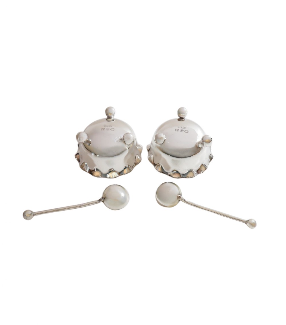 A pair of Victorian sterling silver open salt cellars with crimped rims and matching spoons set inside a blue velvet presentation case. View VIII