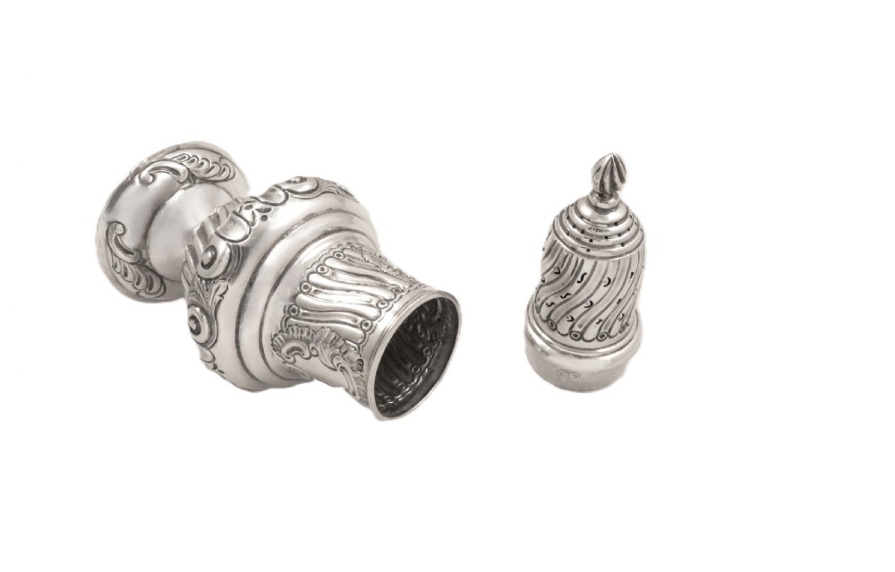 An Edwardian sterling silver sugar castor featuring a spirally fluted pierced dome lid, embossed scroll cartouche, and a turned pedestal foot. View III