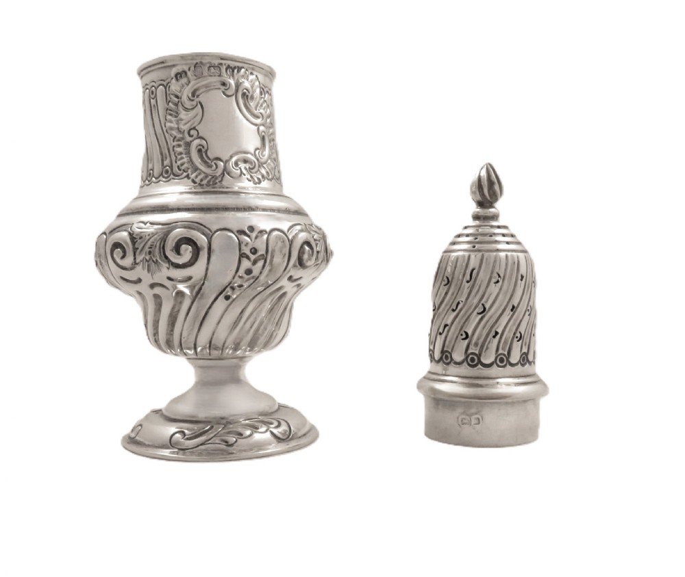 An Edwardian sterling silver sugar castor featuring a spirally fluted pierced dome lid, embossed scroll cartouche, and a turned pedestal foot. View VIII