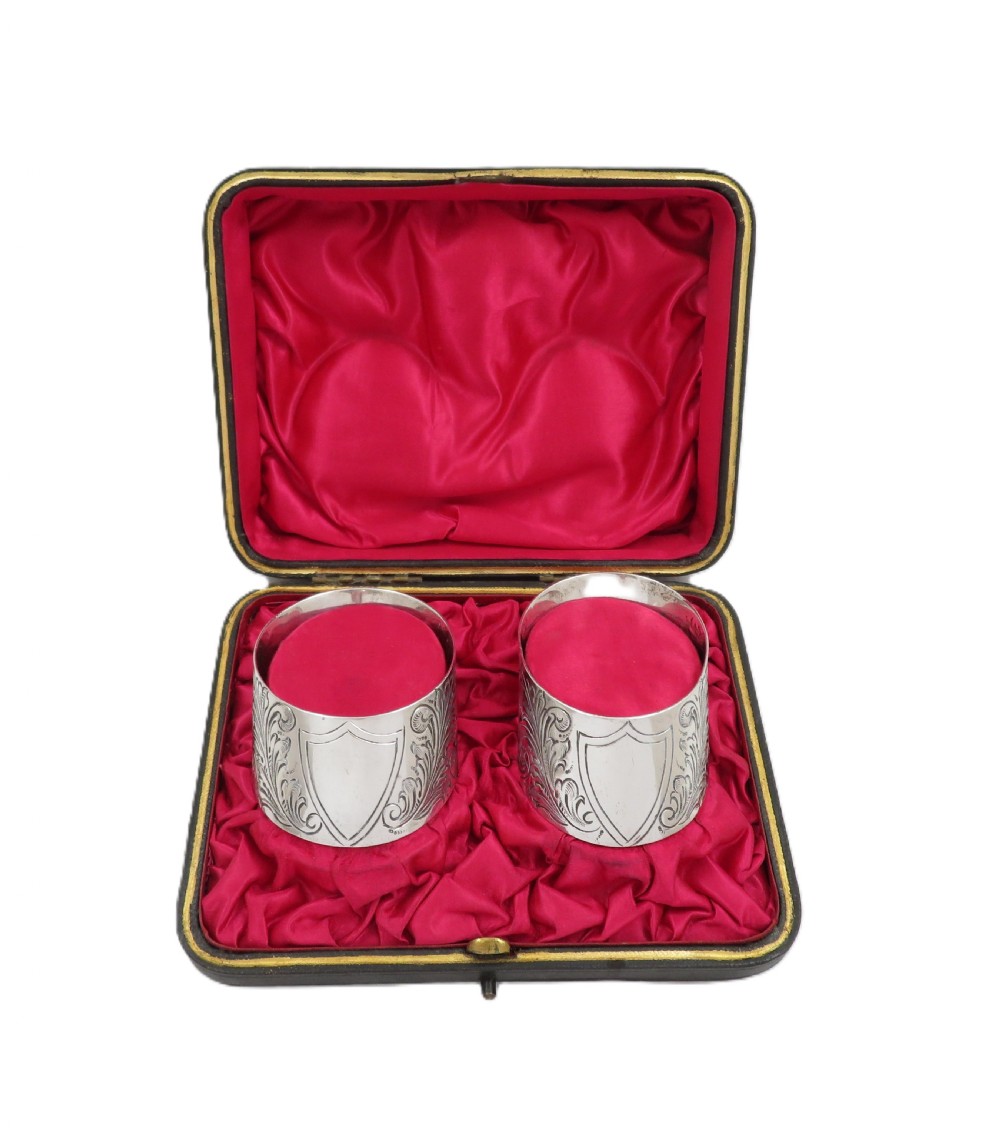 A pair of engraved Victorian sterling silver napkin rings set inside a red silk and velvet lined presentation box. View V