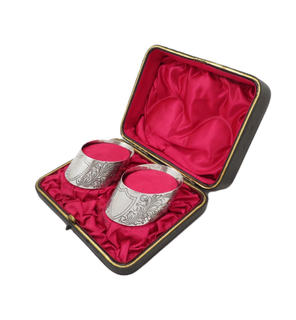 A pair of engraved Victorian sterling silver napkin rings set inside a red silk and velvet lined presentation box. View IX