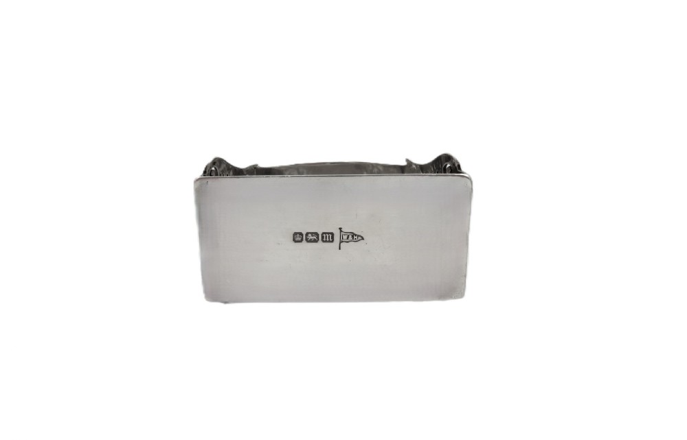 An engraved sterling silver napkin ring resting inside an open red leather presentation case lined with dark red velvet and cream silk. View III