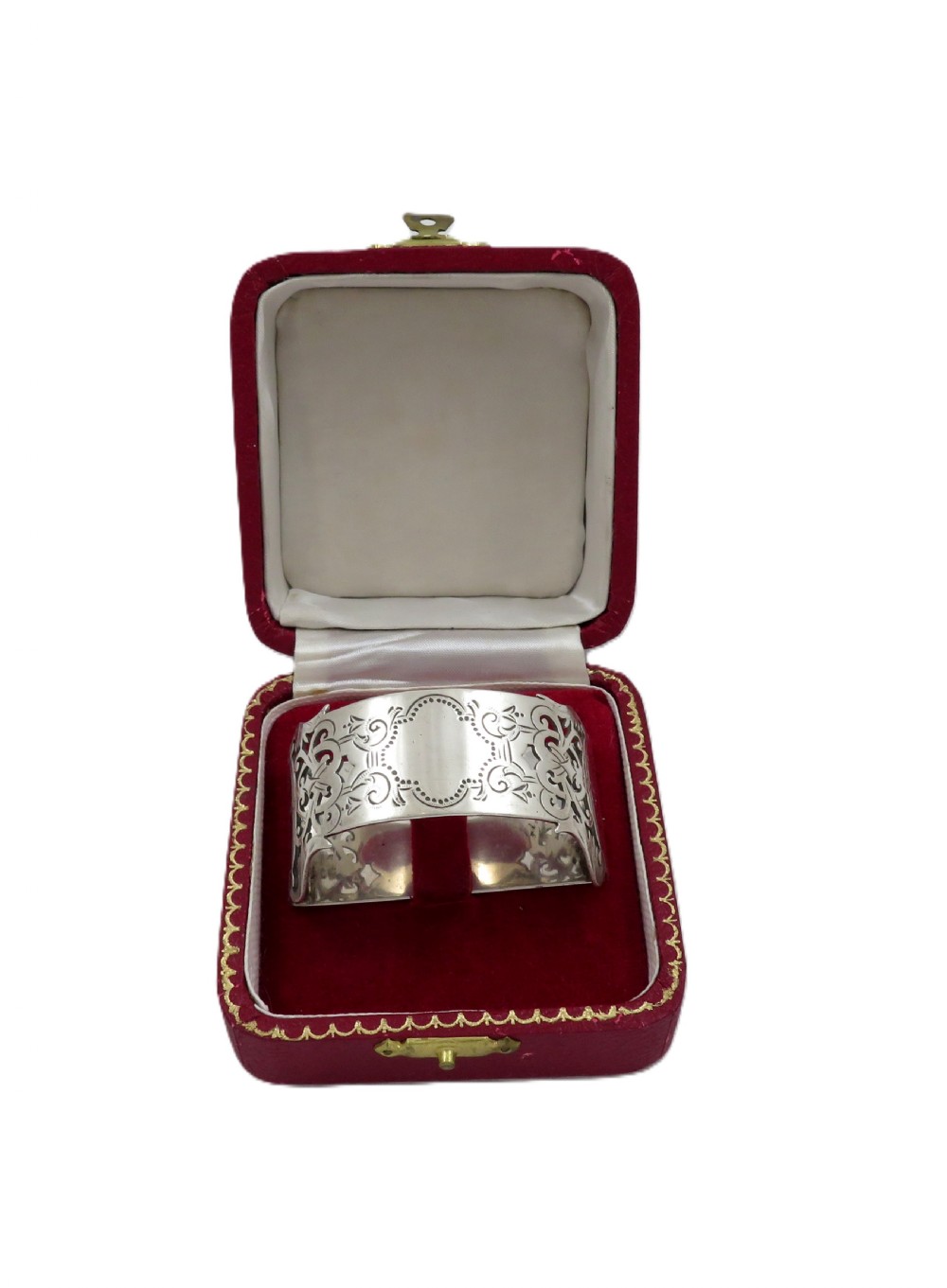An engraved sterling silver napkin ring resting inside an open red leather presentation case lined with dark red velvet and cream silk. View V