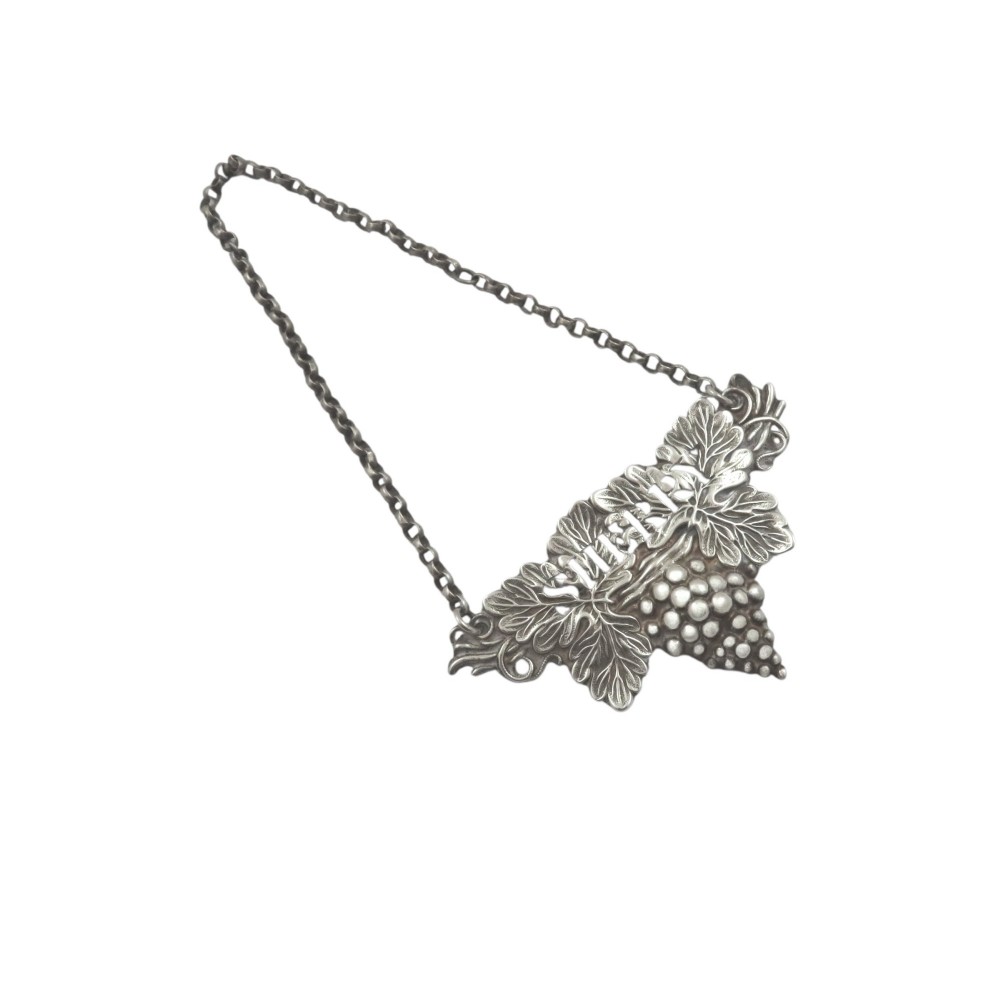 An antique sterling silver decanter label formed as grapevine leaves and a bunch of grapes, featuring the word Sherry in raised lettering with a suspension chain.
