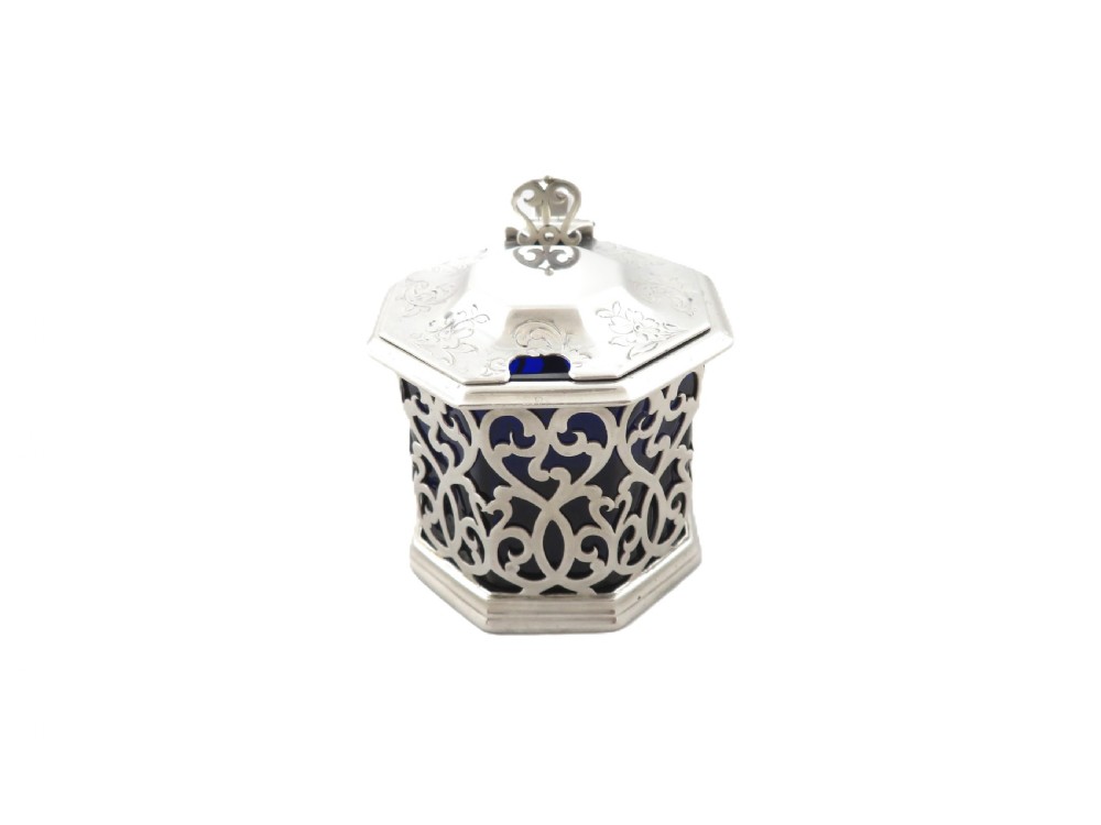An octagonal Victorian sterling silver mustard pot featuring pierced scrollwork and a cobalt blue glass liner. View IV