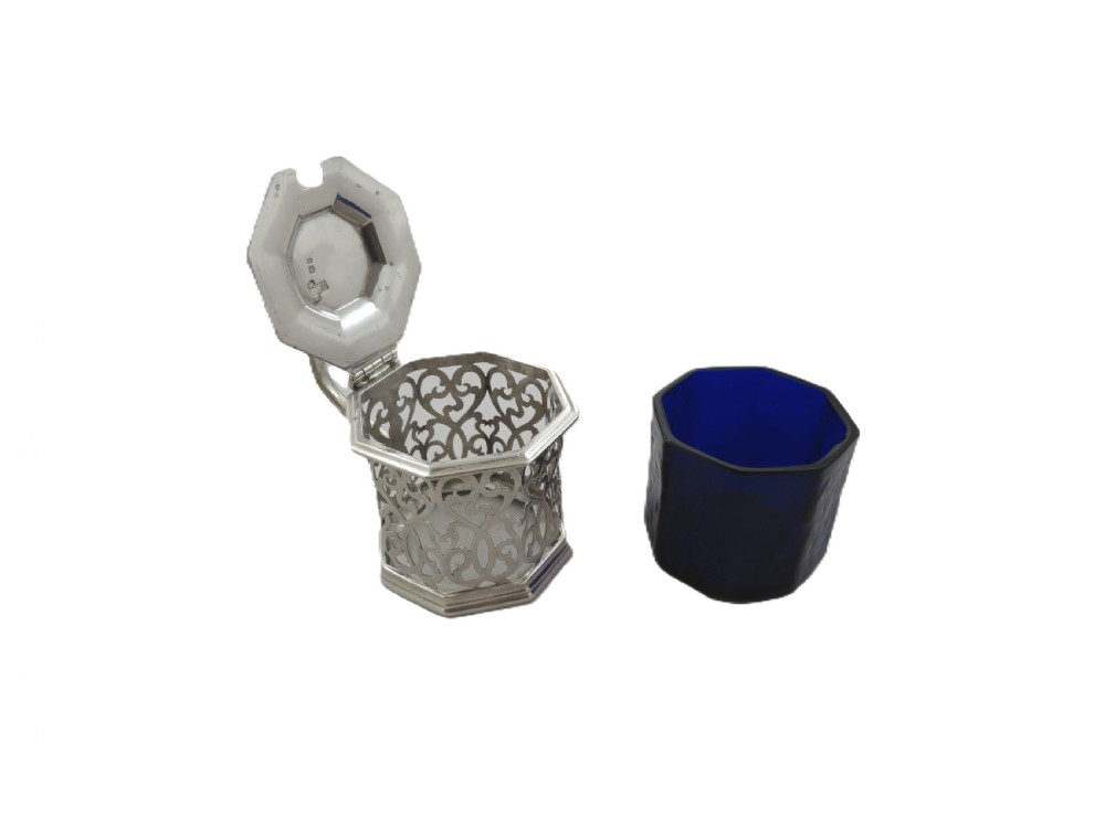 An octagonal Victorian sterling silver mustard pot featuring pierced scrollwork and a cobalt blue glass liner. View V