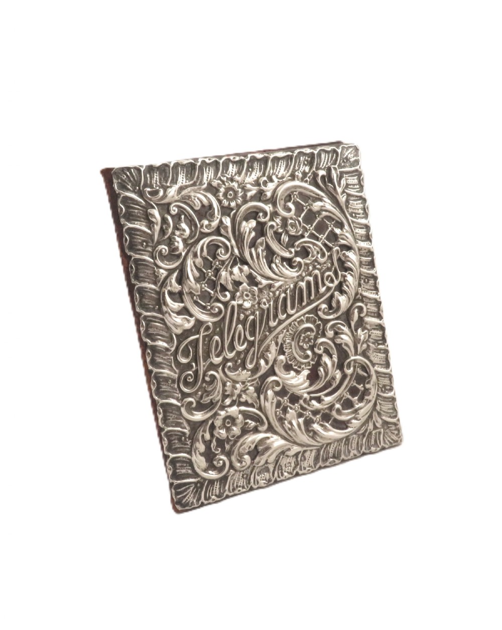 An Edwardian sterling silver telegram folder cover featuring relief scrollwork, floral motifs, and embossed lettering reading Telegrams. View IX