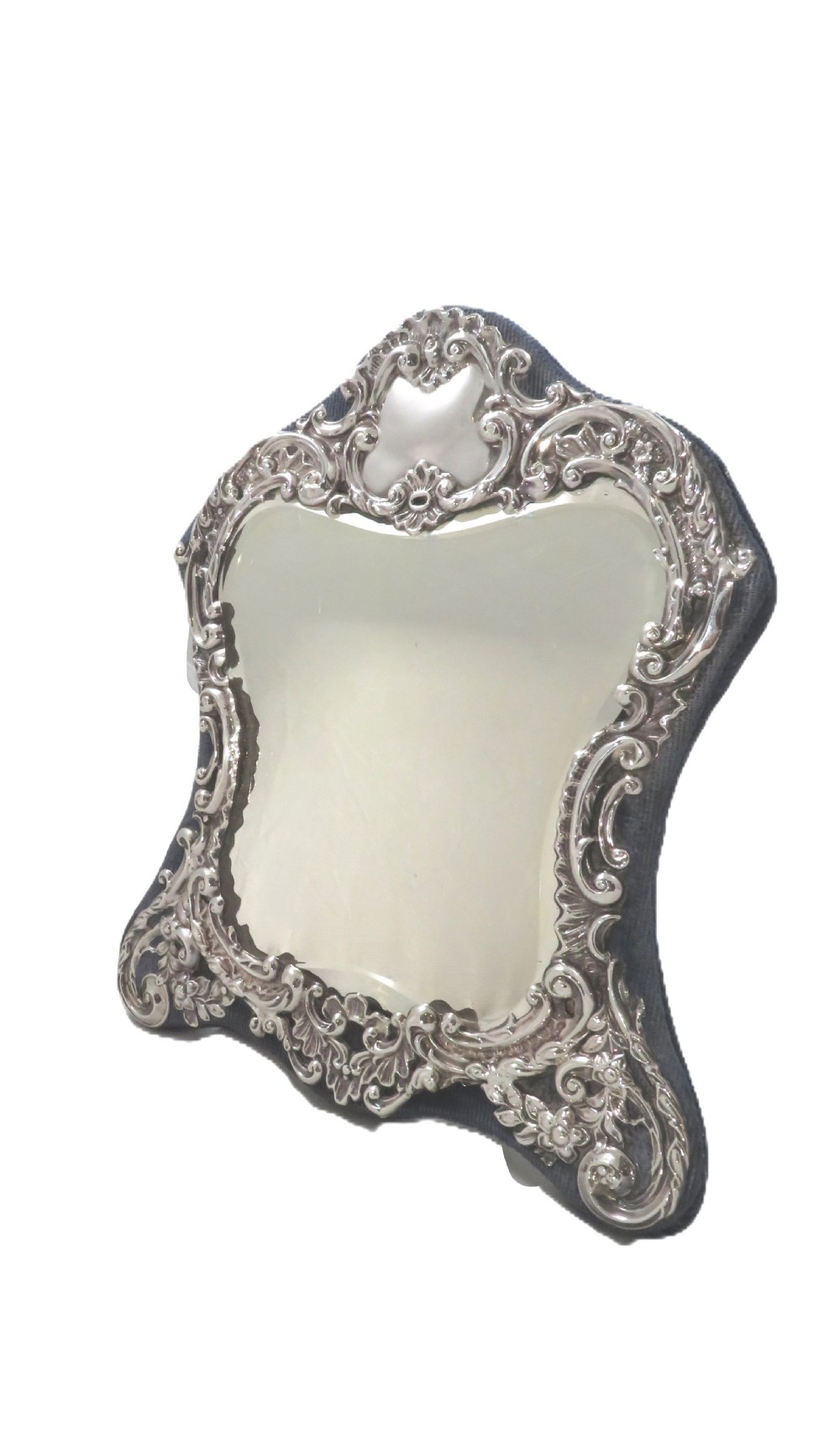 A Victorian sterling silver easel mirror featuring intricate floral repousse decoration and a dark blue velvet backing. View VIII