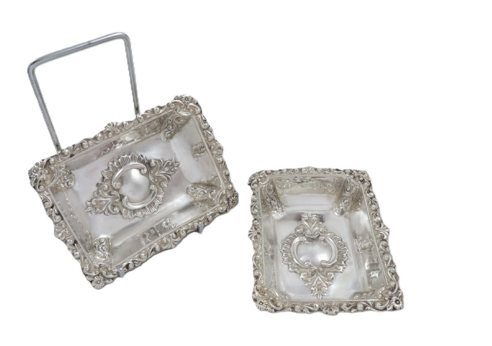 A pair of rectangular embossed sterling silver dishes with ornate scrolled borders, displayed inside a silk and velvet-lined dark presentation case. View III