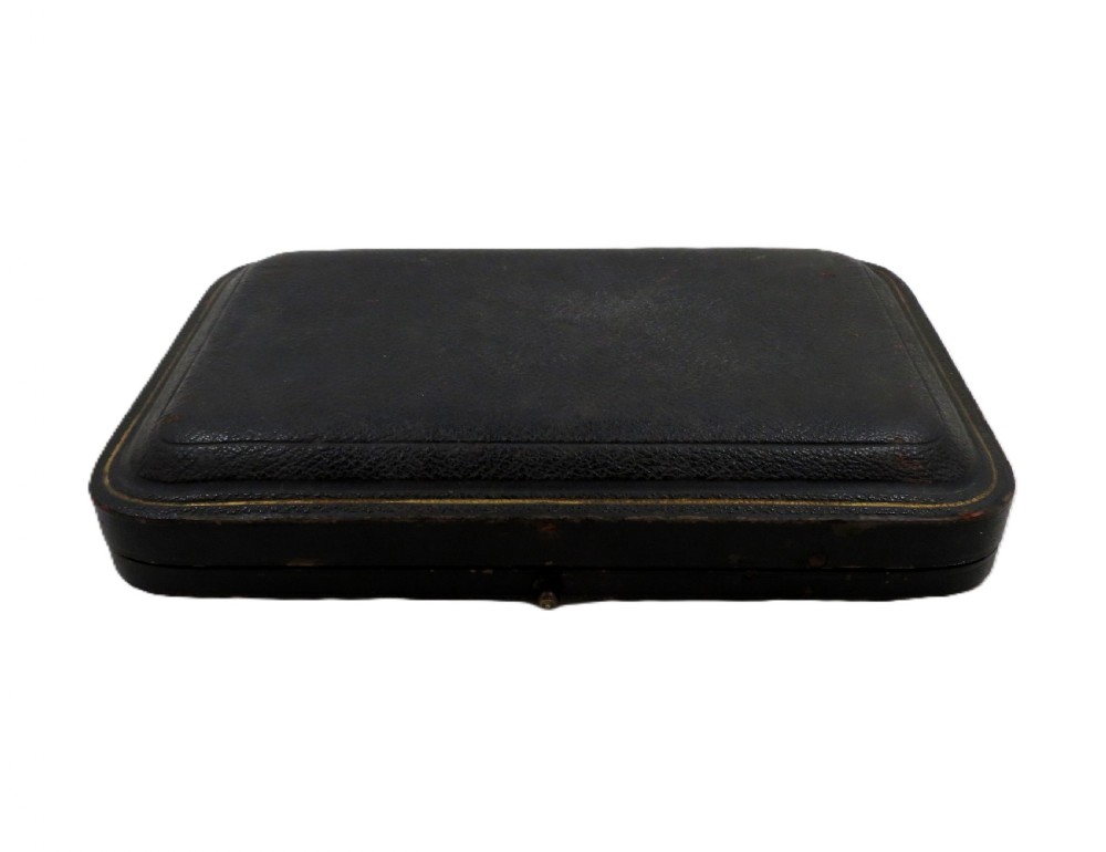 A pair of rectangular embossed sterling silver dishes with ornate scrolled borders, displayed inside a silk and velvet-lined dark presentation case. View V