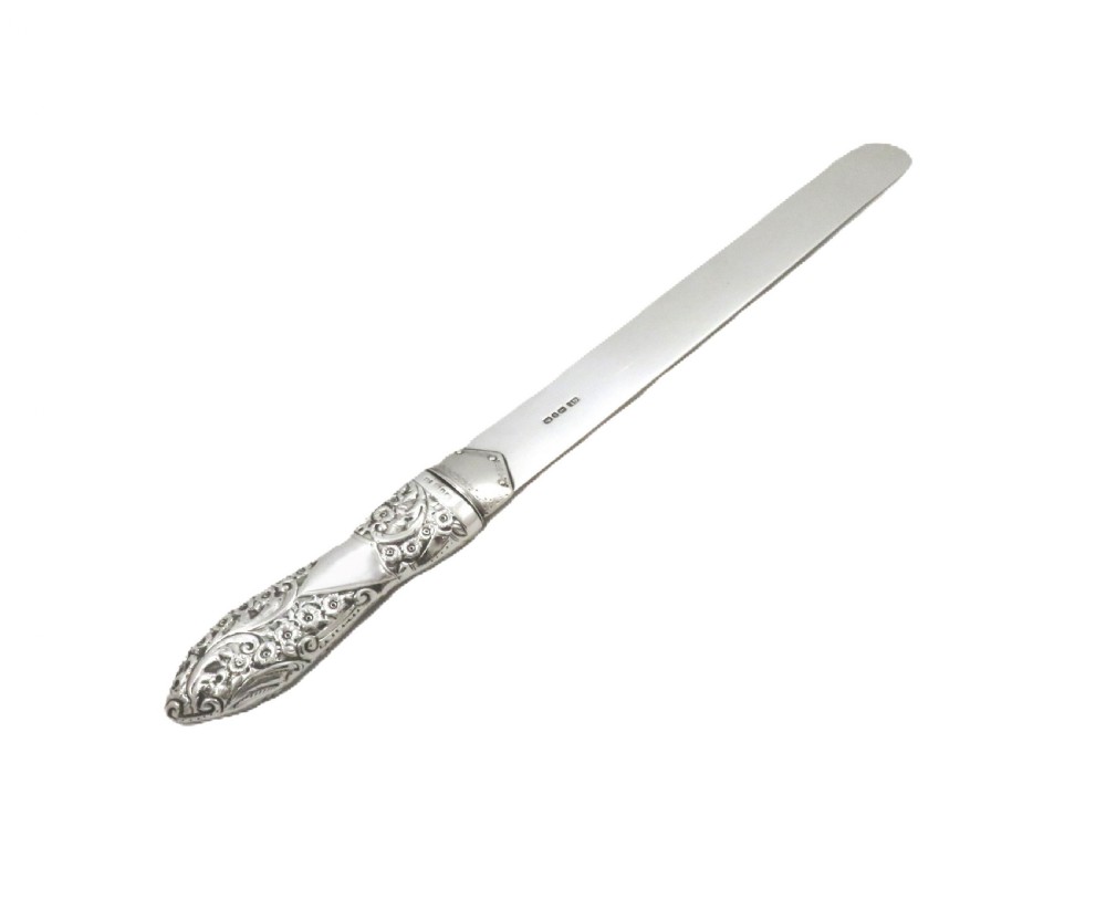 A Victorian sterling silver page turner featuring a flat polished blade stamped with British hallmarks and a heavily embossed foliate handle. View IX