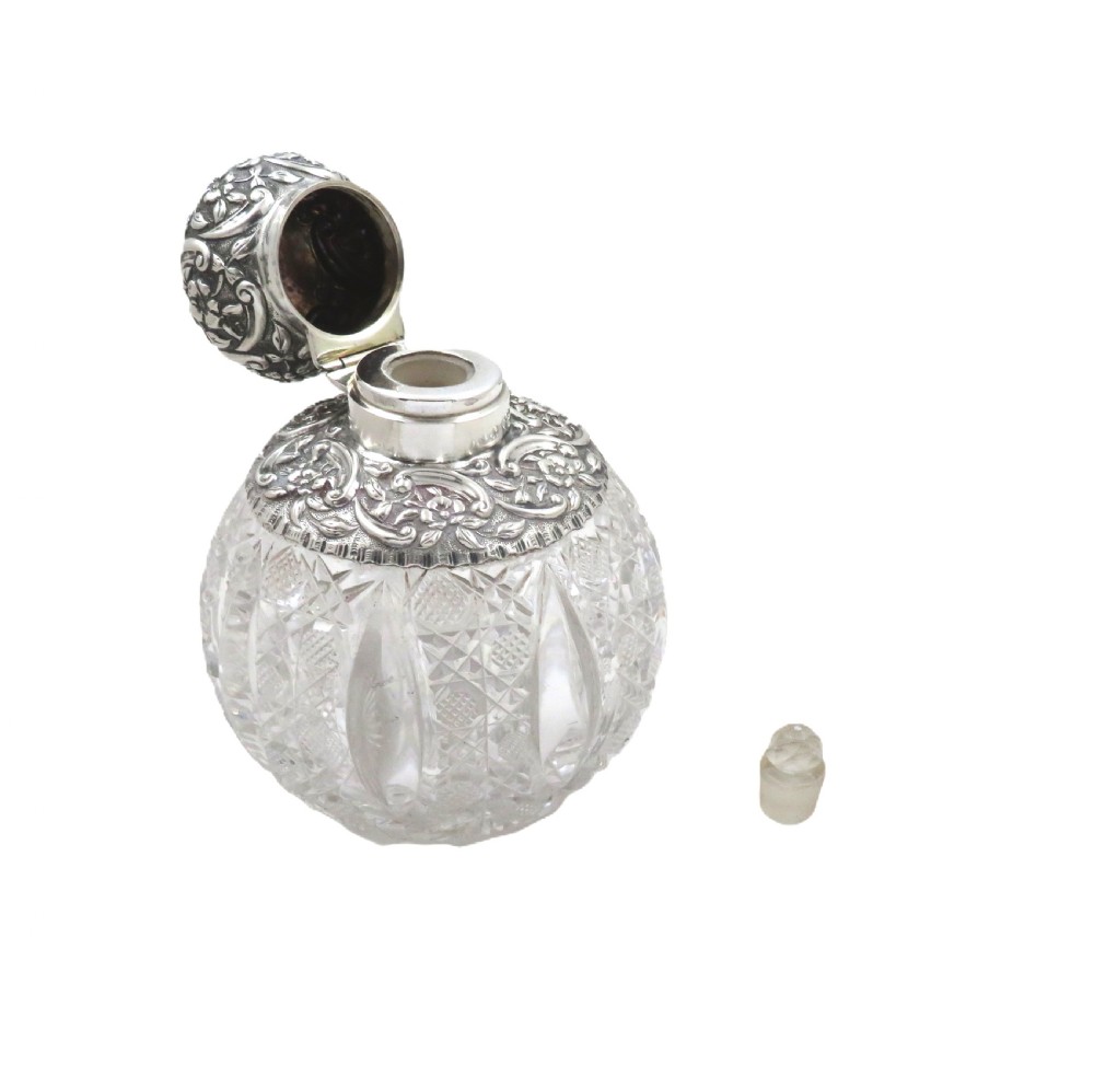 A globular clear cut-glass scent bottle featuring an ornate repousse sterling silver collar and matching spherical silver top. View III