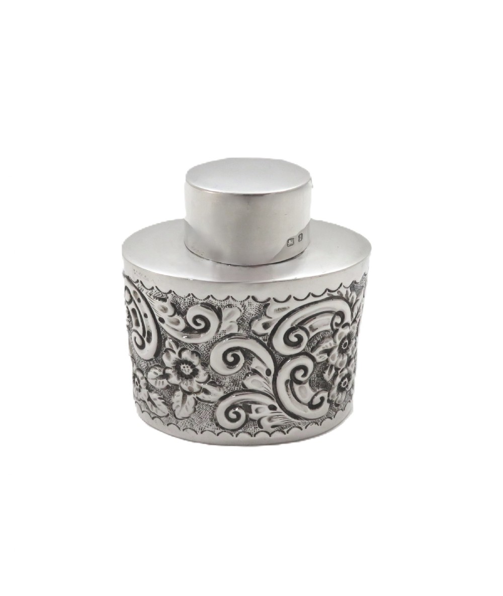 An antique late Victorian sterling silver tea caddy featuring repousse floral scroll decoration and a smooth fitted cap lid. View III