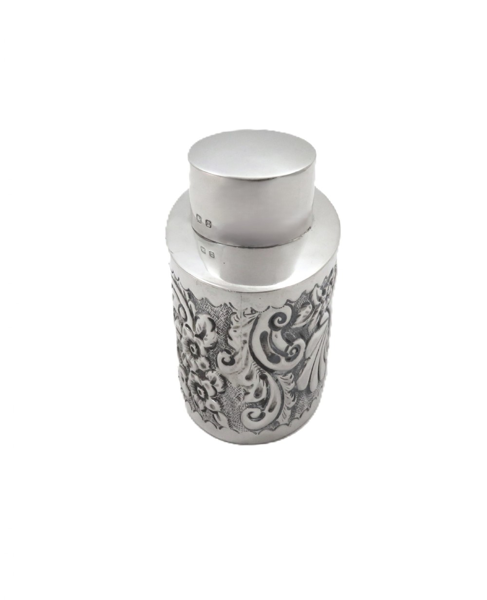 An antique late Victorian sterling silver tea caddy featuring repousse floral scroll decoration and a smooth fitted cap lid. View V